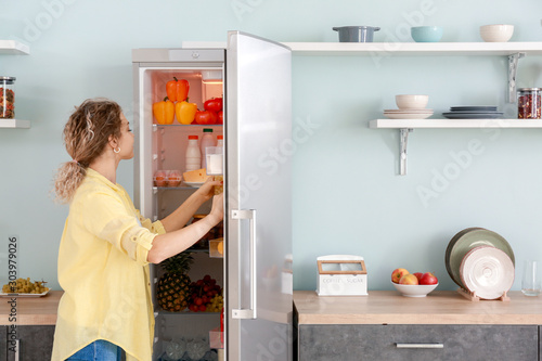 Woman choosing food in modern fridge at home photo