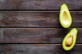 Avocado - whole and halfs - frame on dark wooden background top view copy space