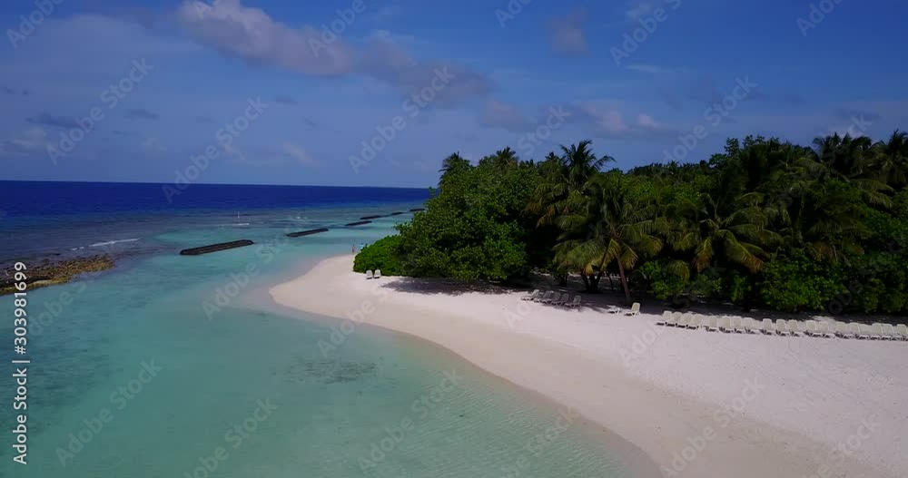 Sunbeds on exotic beach with white sand hidden paradise under palm trees in front of calm and clear shallow water bordered by barriers in Maldives Sunbeds on exotic beach with white sand hidden paradise under palm trees in front of calm and clear shallow water bordered by barriers in Maldives