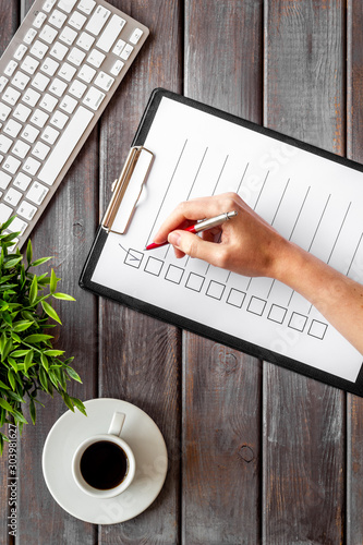 Hand fill checklist on dark wooden office background top view