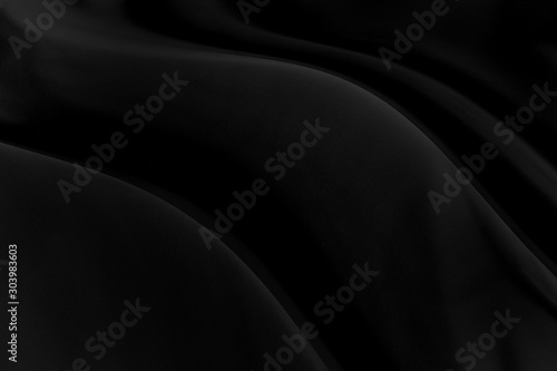 Black gray satin dark fabric texture luxurious shiny that is abstract silk cloth background with patterns soft waves blur beautiful.