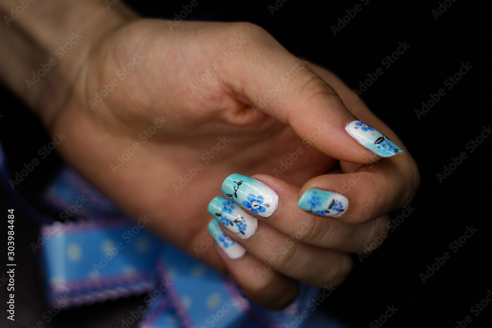 Blue manicure with a flower pattern, and a bow in hand