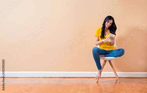 Young woman using her tablet sitting in a chair © Tierney