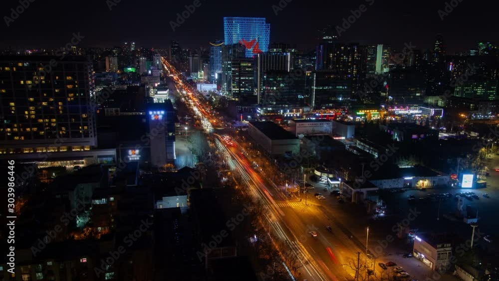 Timelapse illuminated Chinese highway with automobiles in heavy traffic surrounded by flashing advertisement lights on Beijing highrise buildings