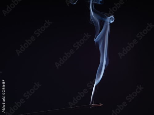 Steam of white smoke from burning incense, isolated on black background, close up view. Structure of smoke, brush effect. Abstract background of smouldering sweet smell. Smell for meditation
