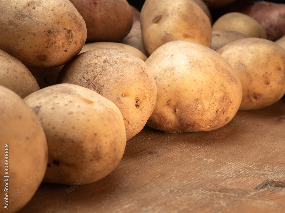 Rustic potatoes. Vegetables from farmhouse field is lying in bulk on wooden table. Looking at vegetables from an angle. Rustic potatoes. Vegetables from farmhouse field is lying in bulk on wooden table. Looking at vegetables from an angle.