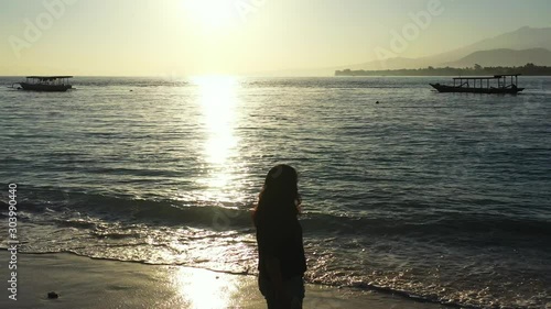 Samoa Island - Tourist enjoying the beautiful sunset by the shoreline of the beach with boats floating by the sea - running shot photo