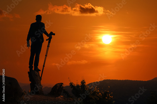 Photographer taking pictures on the mountain over sunset background