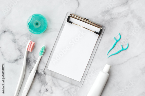 Set of pink and turquoise blue toothbrushes, toothpaste and other tools on marble background. Dental and health care concept. Top view, flat lay. Free copy space. photo