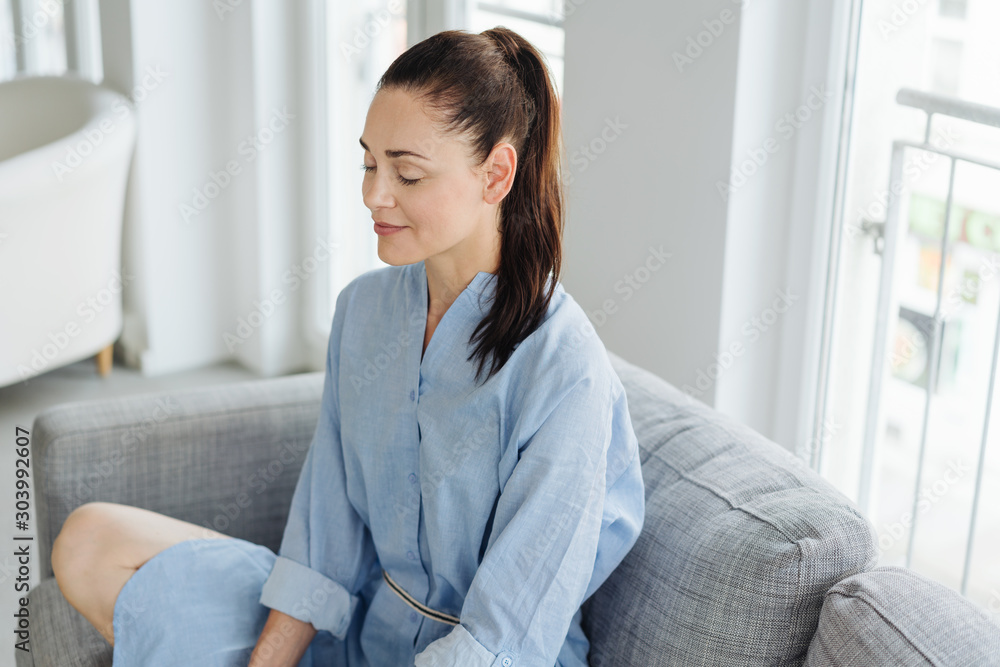 Young woman sitting meditating at home - obrazy, fototapety, plakaty 