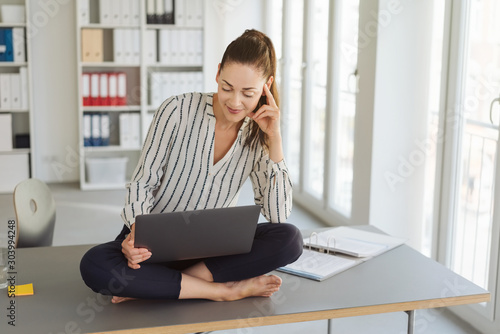 Barefoot young woman using a laptop computer