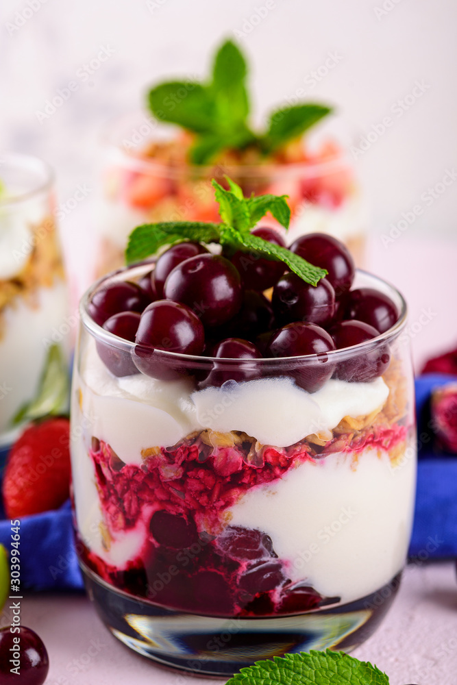 vertical image of dessert with cherries, whipped cream, granola and mint on light pink background vertical image of dessert with cherries, whipped cream, granola and mint on light pink background