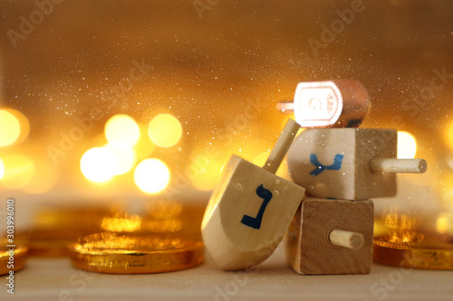 religion concept of of jewish holiday Hanukkah with wooden dreidels (spinning top) and chocolate coins over wooden table and bokeh lights background