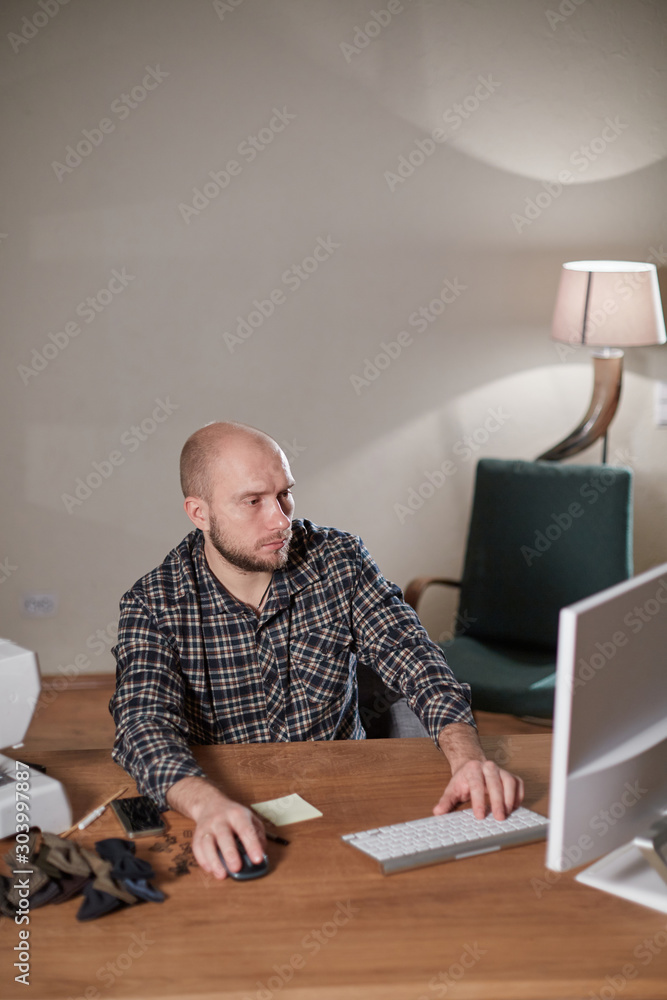 Man on the computer makes out the delivery of the online store. Working with sewing machine in a textile studio. Tailor makes bow ties of woolen fabric. Man on the computer makes out the delivery of the online store. Working with sewing machine in a textile studio. Tailor makes bow ties of woolen fabric.