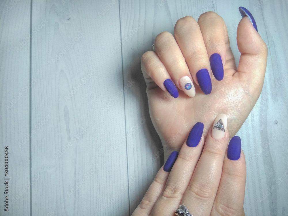 Women's manicure on long round nails. Gel nail Polish matte blue colour  with a camouflage design