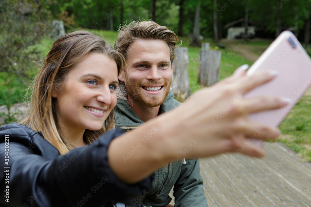 happy young couple in park doing a selfie