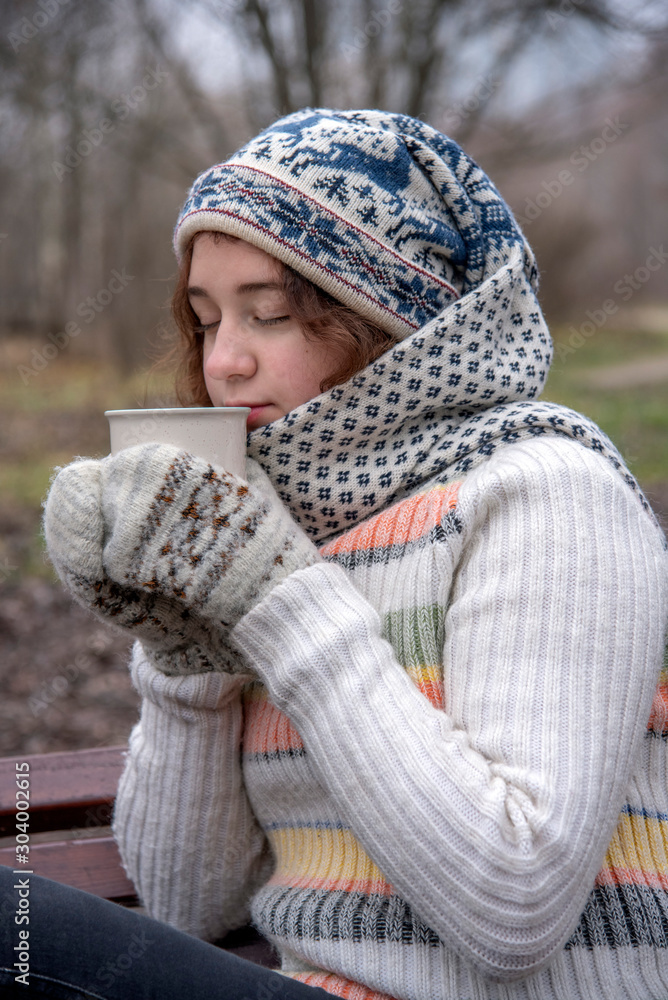 Girl in a funny hat drinking from a mug on the street. Girl in a funny hat drinking from a mug on the street.