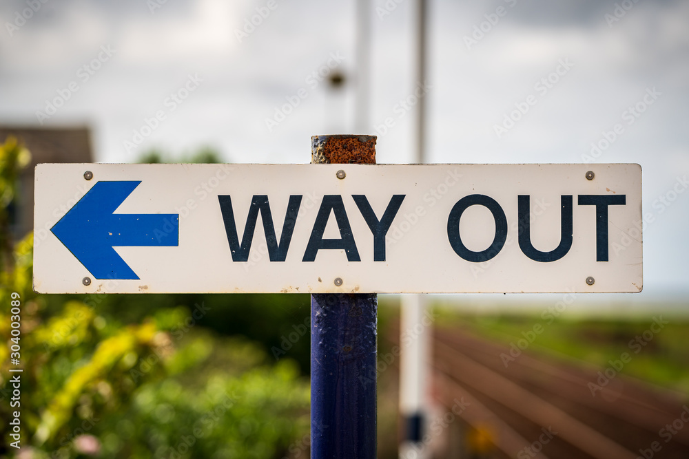 Sign: Way Out, with blurry background, seen in Kirkby-in-Furness, Cumbria, England, UK Sign: Way Out, with blurry background, seen in Kirkby-in-Furness, Cumbria, England, UK