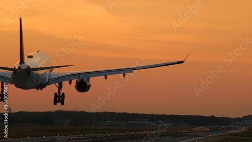 Rear view of twin engine widebody airplane land on at the dawn. Moment of touch the runway.
