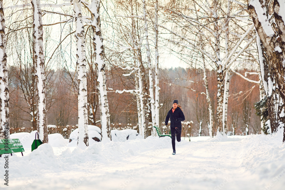 Woman running jogging in the snow in a park in winter.