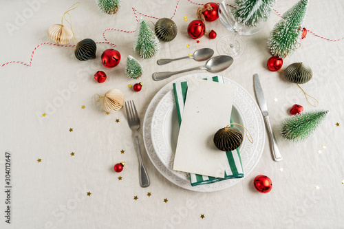 Beautiful table setting on grey background with white plates, glass, cutlery silverware, champagne and Christmas decorations. Holiday layout with copy space.