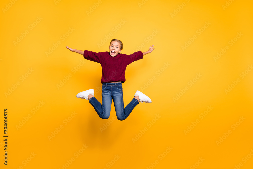 Full length body size view of nice attractive carefree glad girlish cheerful cheery pre-teen girl jumping having fun flying like plane isolated on bright vivid shine vibrant yellow color background