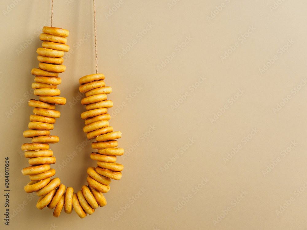 Bagels hang on a string on the yellow wall. Place to add text