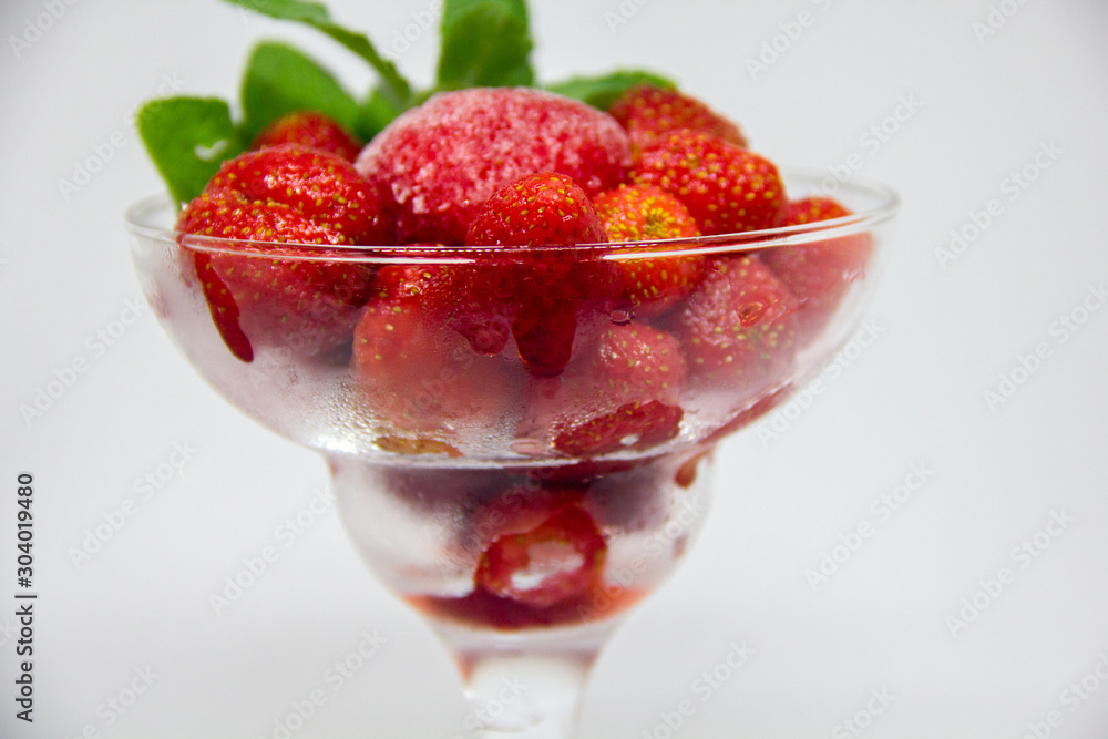 frozen strawberries with mint leaves in a glass on a white background frozen strawberries with mint leaves in a glass on a white background