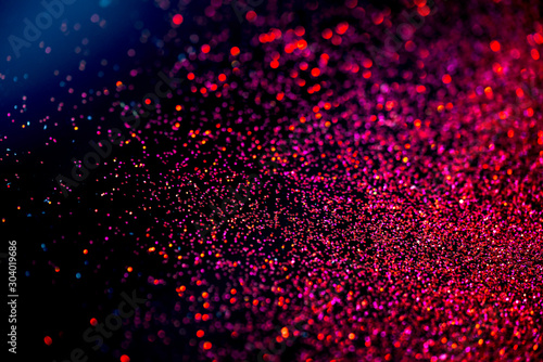 Red/purple shiny glitter on black background with blue light. Macro shot, shalow DOF. photo