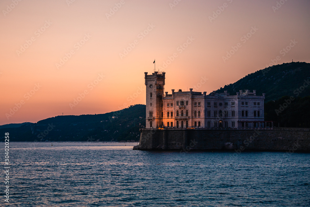 Dramatic view of the tourist spot Castello di Miamare (Castle of Miramare) in Trieste, Italy on the Mediterranean sea coast in europe while sunset.