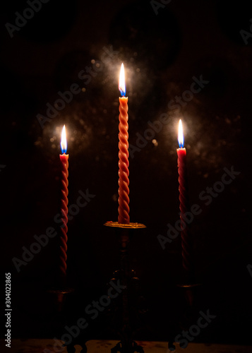  Three red candles burning in the darkness outside the window