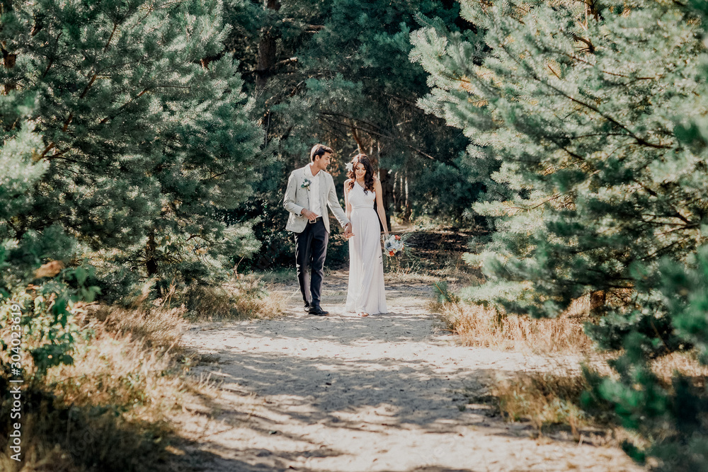 Beautiful newlyweds couple walking in the woods. Honeymooners.