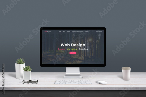 Web design studio concept. Work desk with computer display and modern design web agency page.