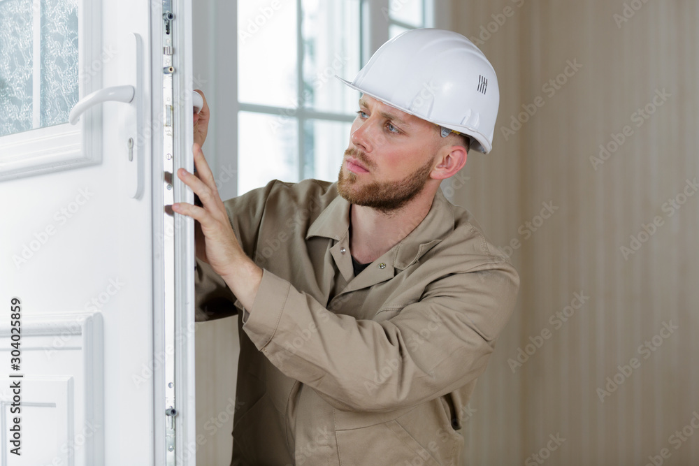 handsome young man installing bay window in a new house handsome young man installing bay window in a new house