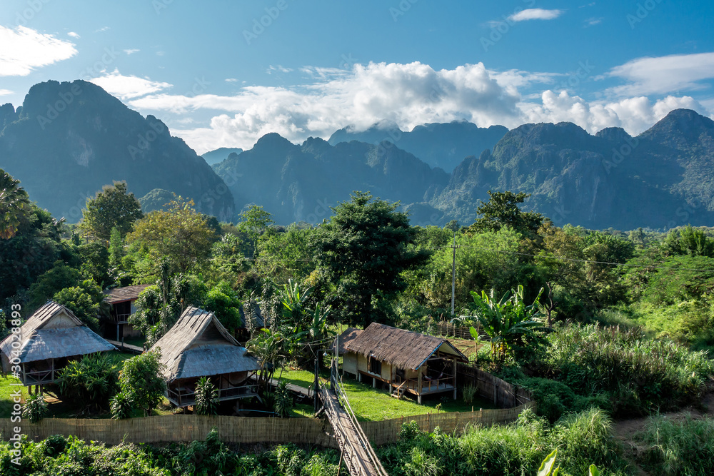 The view at the town called Vang Vieng in Laos with hotels or cottages with the limestone mountain and green forest in the good day. The view at the town called Vang Vieng in Laos with hotels or cottages with the limestone mountain and green forest in the good day.