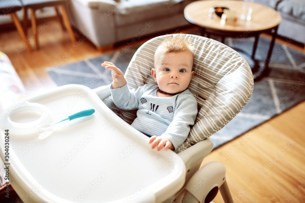 Beautiful caucasian hungry baby boy sitting in his chair and waiting for his mother to feed him. Beautiful caucasian hungry baby boy sitting in his chair and waiting for his mother to feed him.