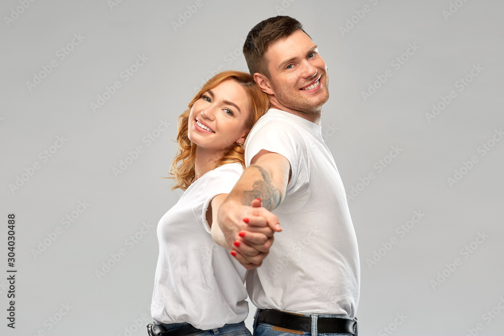 relationships and people concept - happy couple in white t-shirts holding hands over grey background relationships and people concept - happy couple in white t-shirts holding hands over grey background