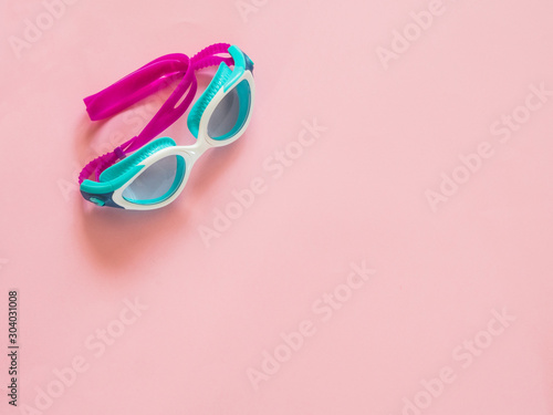 Swimming pool glasses on pink background with copy space