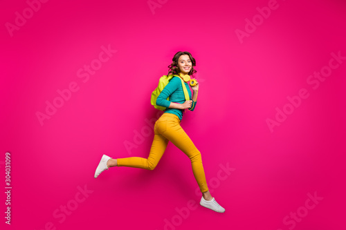 Full length body size side profile photo of cheerful casual cute curly wavy pretty girlfriend wearing white sneakers yellow pants trousers smiling toothily isolated fuchsia vibrant color background