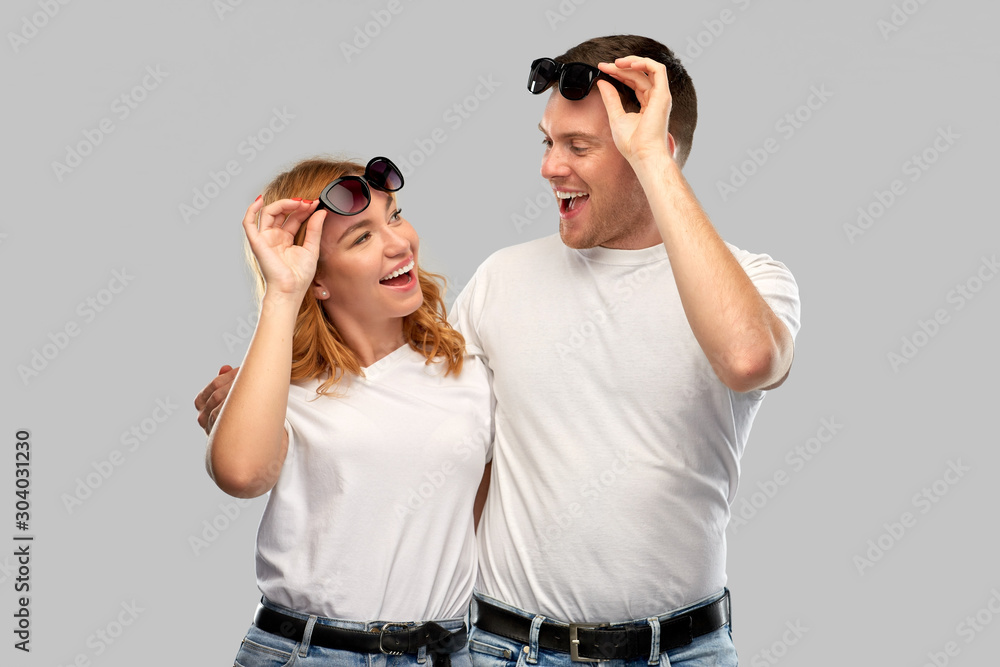 summer accessory, eyewear and people concept - portrait of happy couple in white t-shirts and sunglasses over grey background