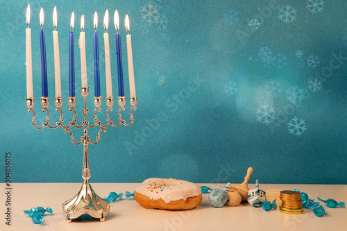 concept of of jewish religious holiday hanukkah with traditinal chandelier menorah, spinning top toys (dreidel), a doughnut and chocolate coins