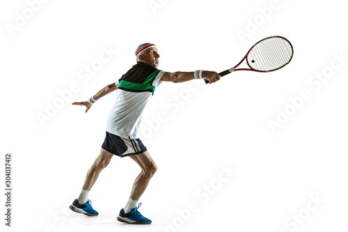 Senior man wearing sportwear playing tennis isolated on white background. Caucasian male model in great shape stays active and sportive. Concept of sport, activity, movement, wellbeing. Copyspace, ad.