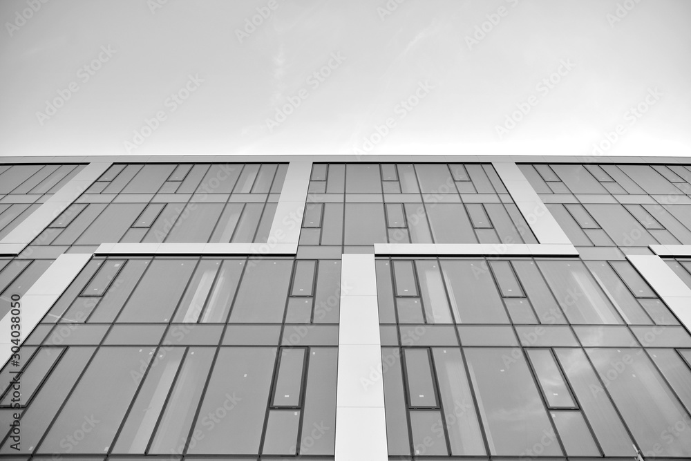 Modern office building wall made of steel and glass with blue sky. Black and white. Modern office building wall made of steel and glass with blue sky. Black and white.