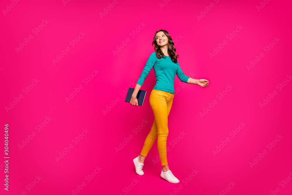 Full length body size turned photo of cheerful wavy curly carefree positive cute pretty sweet girlfriend walking looking back holding copybook isolated bright fuchsia color background