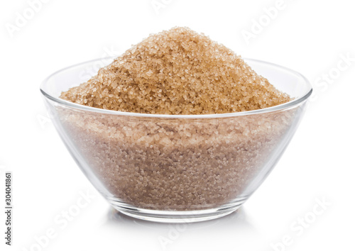 Glass bowl of natural brown refined sugar on white background.