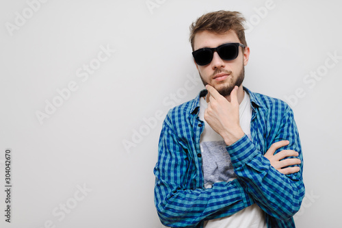Cool hipster man thinking about an idea or solution. Handsome teenager isolated on gray background with copy-space. Thoughtful young man.