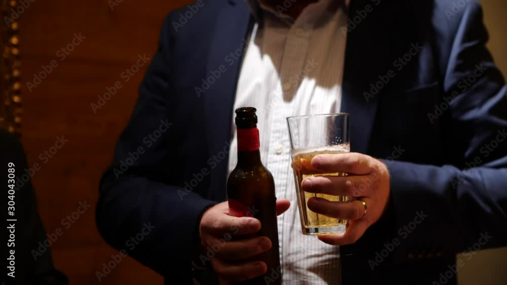 Close up of business man holding a beer, trying to get a point across during his conversation with his colleagues. Drinking awareness, don't drink and drive after a night out, night life, beer culture Close up of business man holding a beer, trying to get a point across during his conversation with his colleagues. Drinking awareness, don't drink and drive after a night out, night life, beer culture