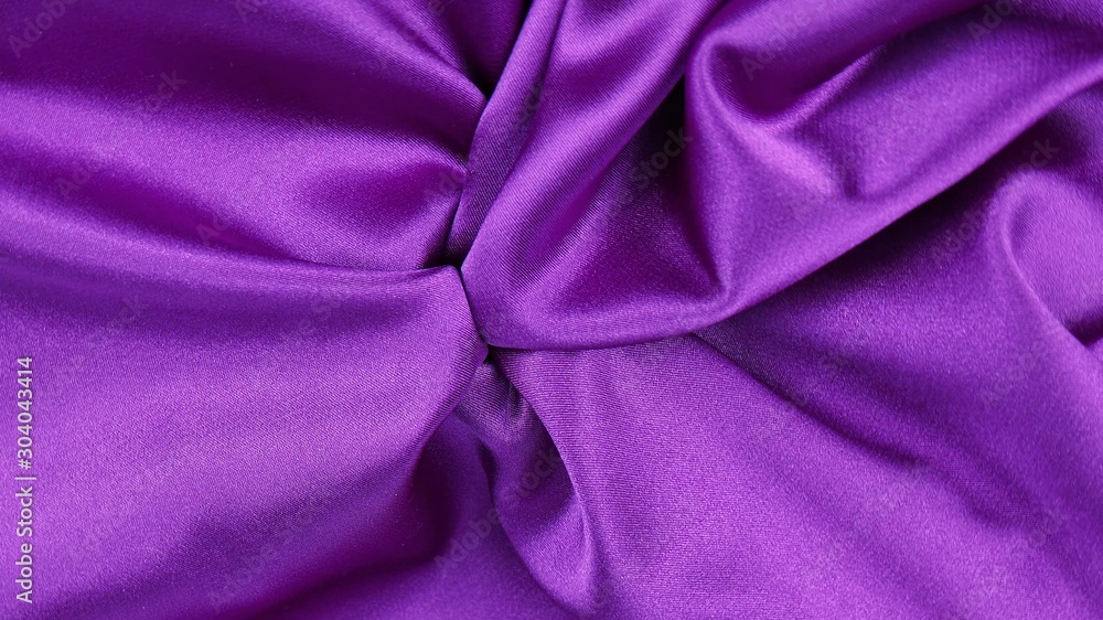 Bright violet satin fabric is draped with soft folds, background Bright violet satin fabric is draped with soft folds, background