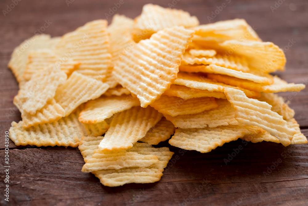 Crispy potato chips on a dark wooden table. Unhealthy food. Fast foot.