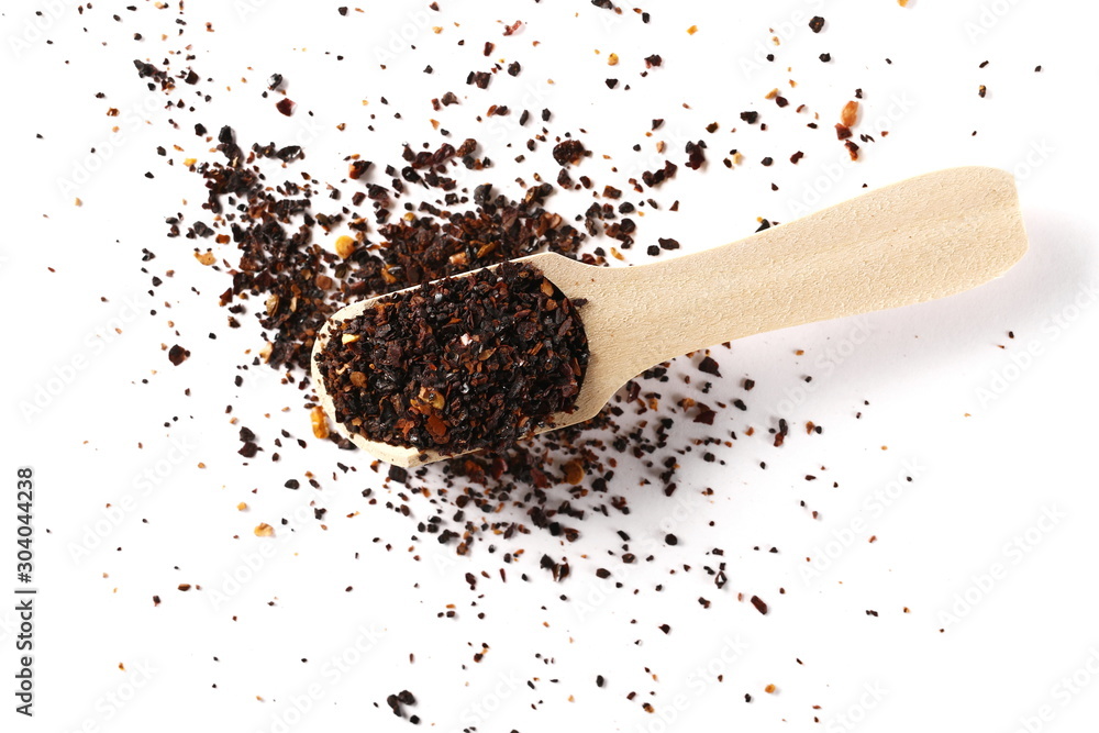 Dry red chili pepper flakes, cut up paprika with wooden spoon isolated on white background, top view Dry red chili pepper flakes, cut up paprika with wooden spoon isolated on white background, top view